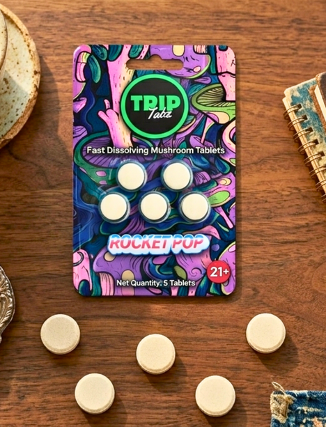 Pack of TRIP Fast Dissolving Mushroom Tablets on a wooden surface with tablets scattered around.